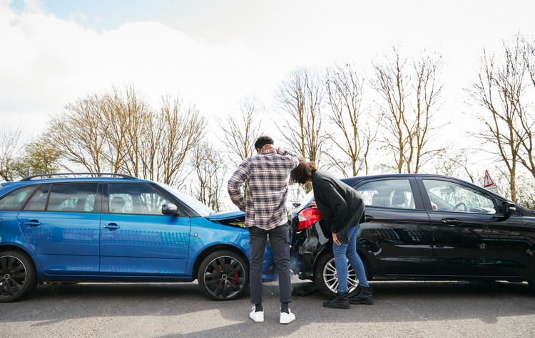 Two person inspect damage to a blue and a black car after a rear-end collision.